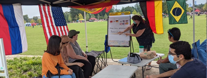 Woman at flip chart under pop up tent teaching several seated students
